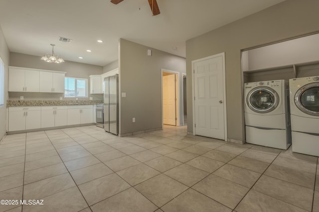 laundry room featuring separate washer and dryer, ceiling fan with notable chandelier, and light tile patterned floors