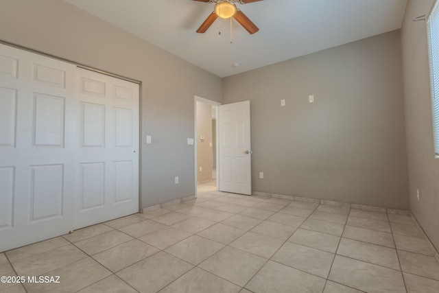 unfurnished bedroom with light tile patterned flooring, ceiling fan, and a closet