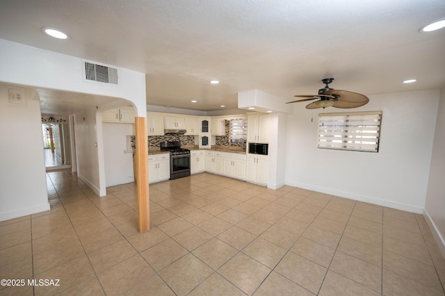 kitchen with ceiling fan, light tile patterned floors, white cabinets, stainless steel gas stove, and backsplash