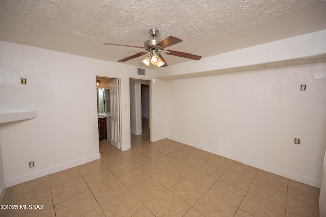 spare room featuring ceiling fan, a textured ceiling, and light tile patterned floors