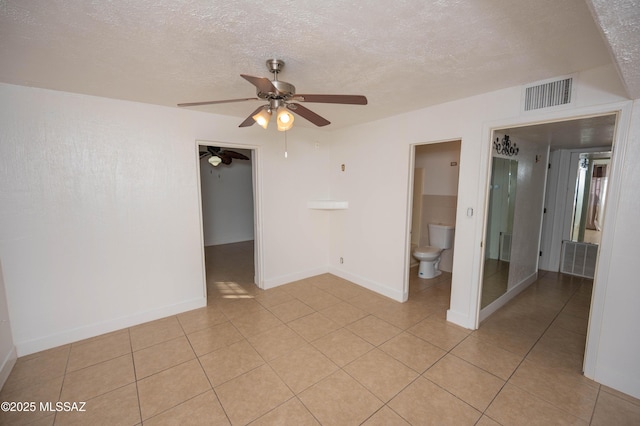 unfurnished room with ceiling fan, light tile patterned floors, and a textured ceiling