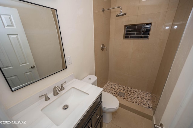 bathroom featuring vanity, toilet, tiled shower, and tile patterned flooring