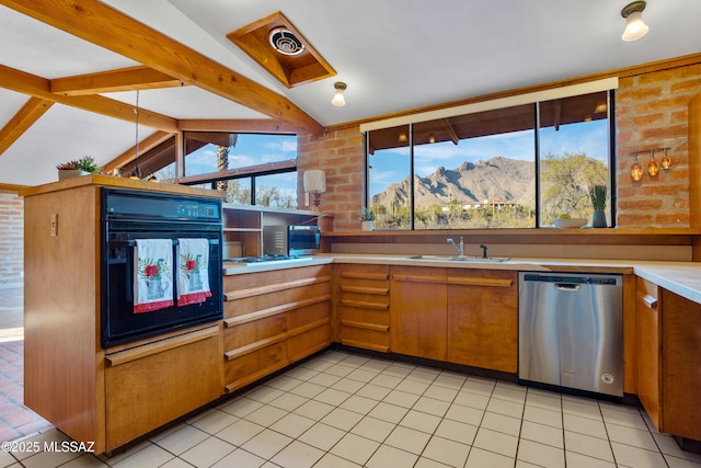 kitchen featuring a mountain view, stainless steel appliances, a sink, light countertops, and brown cabinets