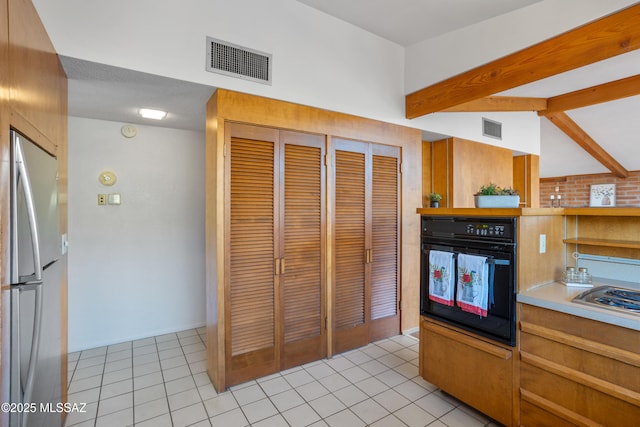 kitchen featuring oven, visible vents, light countertops, and freestanding refrigerator