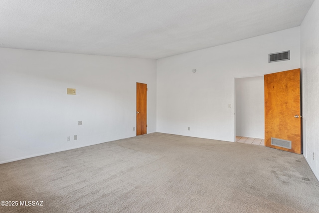 spare room featuring visible vents, vaulted ceiling, and light carpet