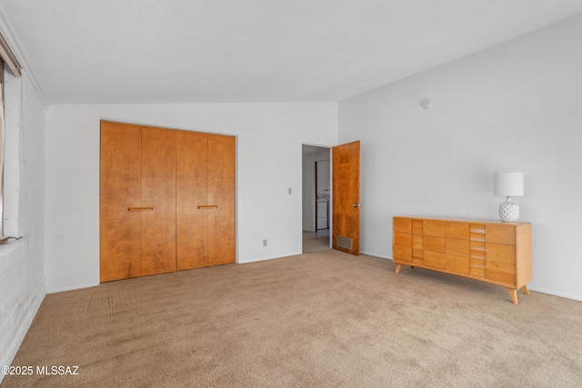 unfurnished bedroom featuring vaulted ceiling and light carpet