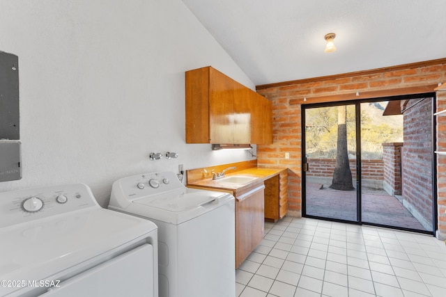 laundry area featuring light tile patterned floors, a sink, brick wall, washer and dryer, and laundry area