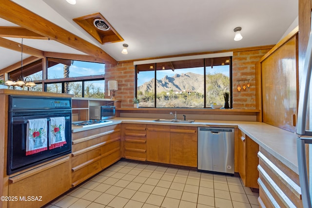 kitchen featuring lofted ceiling with beams, appliances with stainless steel finishes, light countertops, a mountain view, and a sink