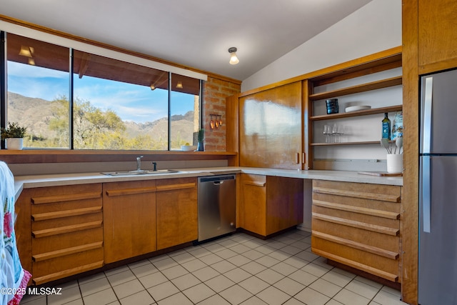 kitchen with vaulted ceiling, stainless steel appliances, light countertops, a mountain view, and a sink