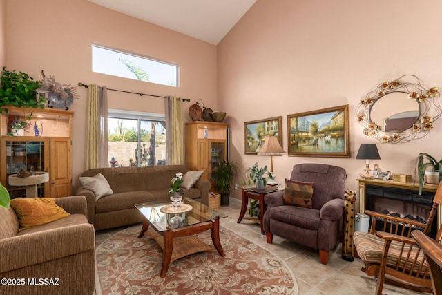 living room with high vaulted ceiling, a glass covered fireplace, and light tile patterned flooring