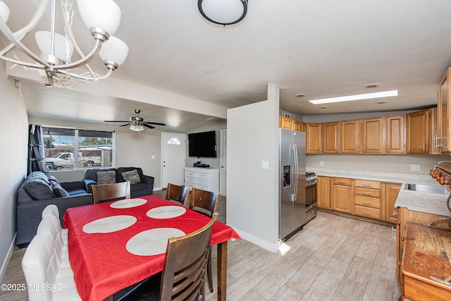 dining room with ceiling fan with notable chandelier, light hardwood / wood-style flooring, and sink