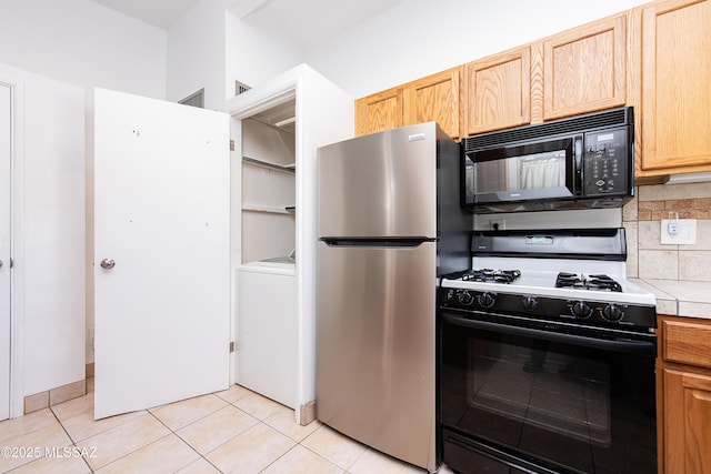 kitchen featuring tasteful backsplash, stainless steel refrigerator, light brown cabinets, light tile patterned floors, and range with gas stovetop