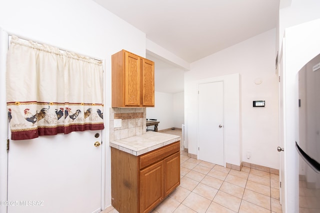 kitchen featuring backsplash, light tile patterned floors, and tile countertops