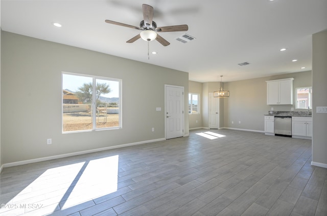 unfurnished living room featuring plenty of natural light, sink, and ceiling fan with notable chandelier