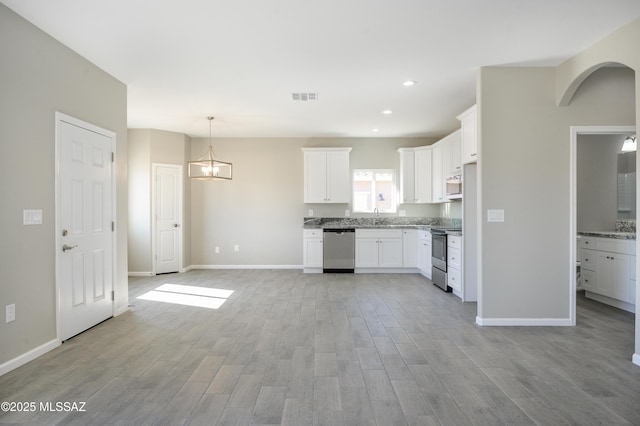 kitchen featuring white cabinets, appliances with stainless steel finishes, sink, and a notable chandelier