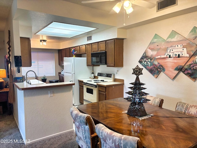 kitchen with kitchen peninsula, sink, ceiling fan, dark carpet, and white appliances