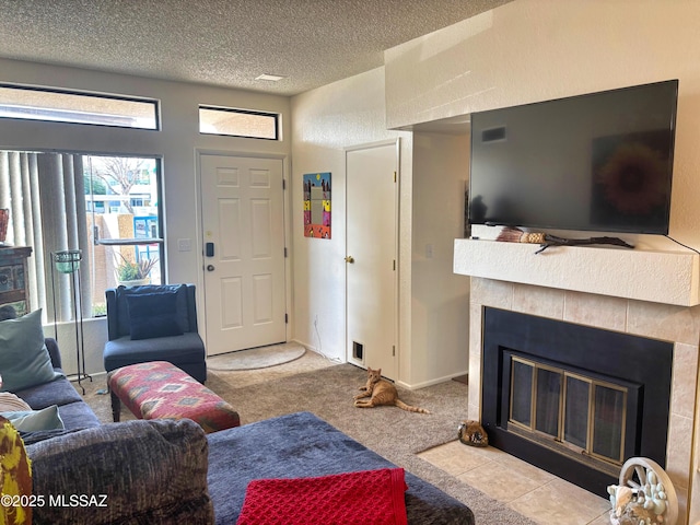 carpeted living room with a tiled fireplace and a textured ceiling