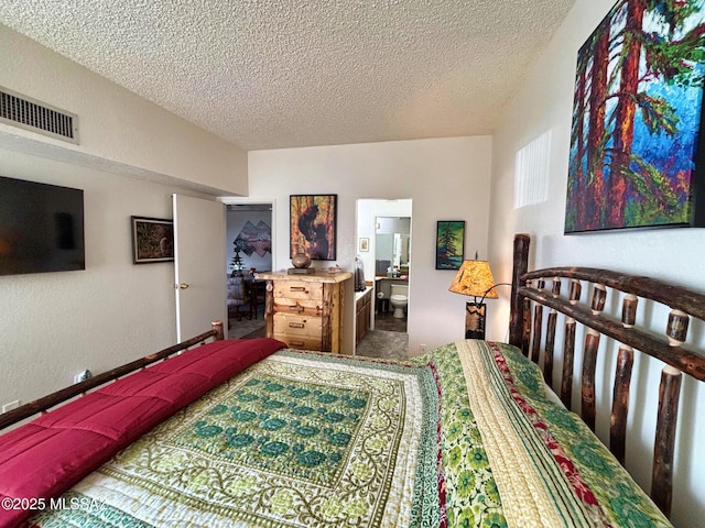 carpeted bedroom featuring a textured ceiling and ensuite bath