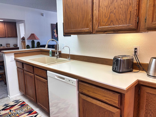 kitchen with white dishwasher, kitchen peninsula, sink, and a textured ceiling