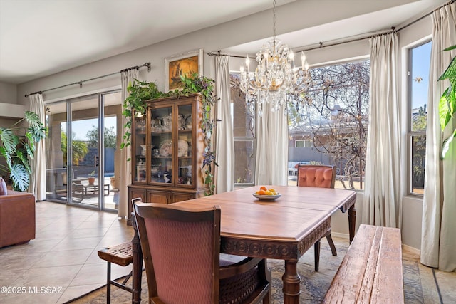 dining area with light tile patterned flooring, plenty of natural light, and a notable chandelier