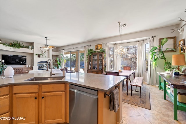 kitchen featuring pendant lighting, stainless steel dishwasher, sink, light tile patterned floors, and ceiling fan with notable chandelier