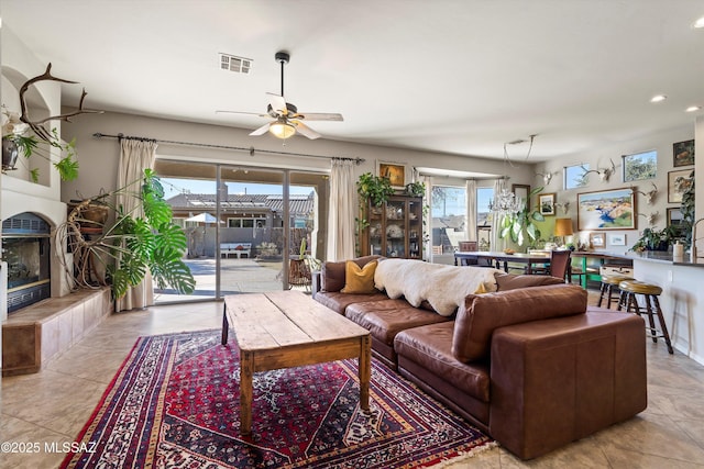 living room featuring ceiling fan, light tile patterned floors, and a fireplace