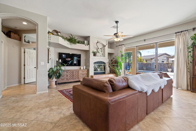 living room featuring ceiling fan, light tile patterned floors, and a tiled fireplace