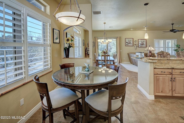 dining space with ceiling fan with notable chandelier