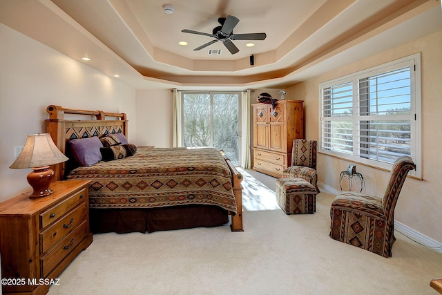 bedroom featuring light colored carpet, a raised ceiling, and ceiling fan