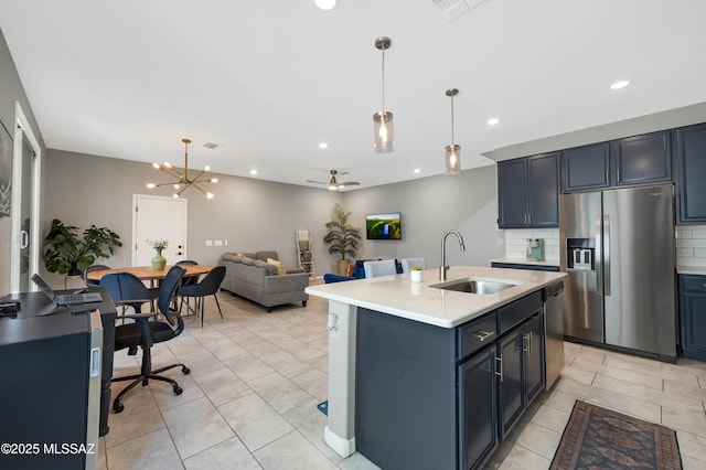 kitchen featuring stainless steel appliances, decorative light fixtures, sink, and a center island with sink