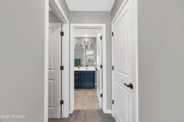 corridor with sink and light colored carpet