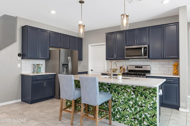 kitchen featuring stainless steel appliances, hanging light fixtures, sink, and a center island with sink