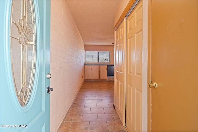 hall with light tile patterned flooring and a textured ceiling