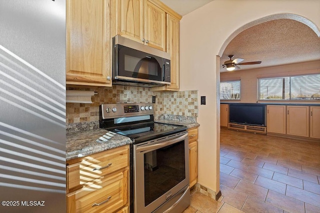 kitchen with tasteful backsplash, light tile patterned floors, ceiling fan, stainless steel appliances, and light stone countertops