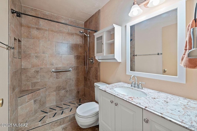 bathroom with a tile shower, vanity, and toilet