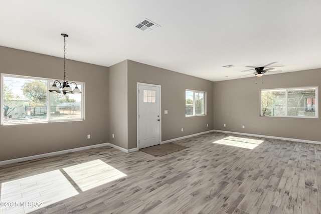 interior space with ceiling fan with notable chandelier and light hardwood / wood-style flooring