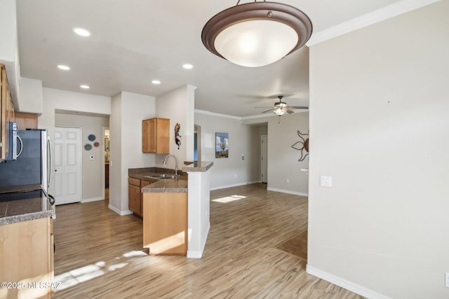 kitchen with sink, light hardwood / wood-style flooring, stainless steel appliances, and kitchen peninsula