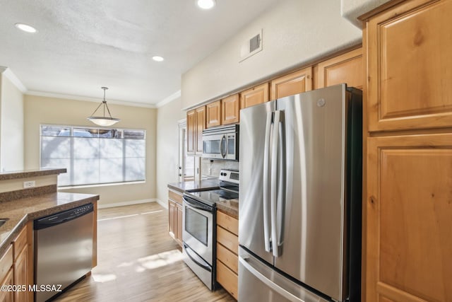 kitchen featuring ornamental molding, appliances with stainless steel finishes, pendant lighting, and light wood-type flooring