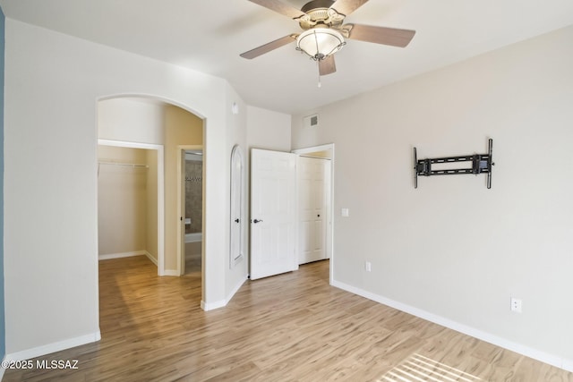 unfurnished bedroom with a spacious closet, light hardwood / wood-style floors, a closet, and ceiling fan