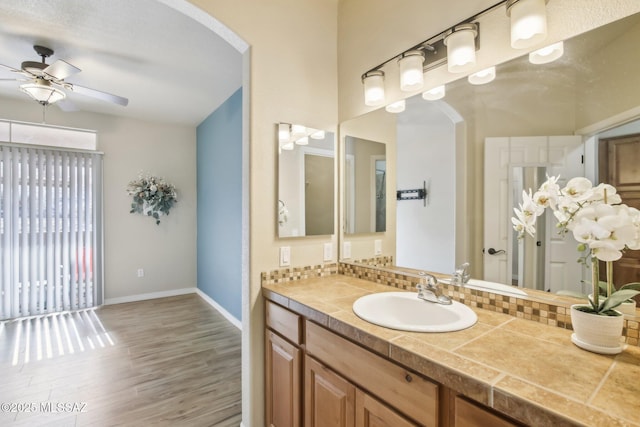 bathroom featuring vanity, decorative backsplash, ceiling fan, and hardwood / wood-style flooring