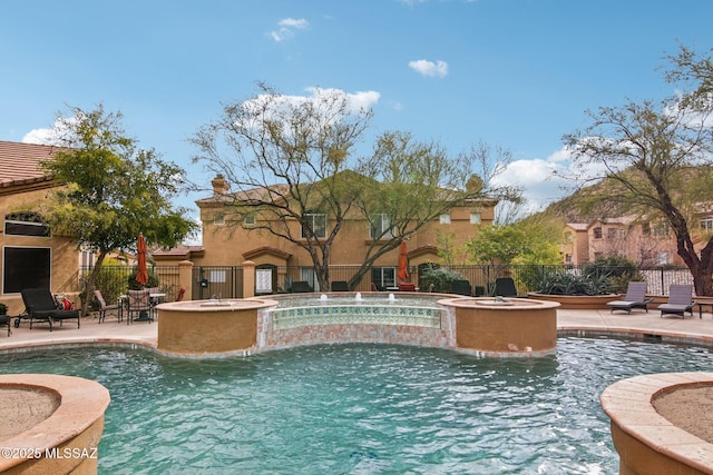 view of pool featuring an in ground hot tub, pool water feature, an outdoor fire pit, and a patio area