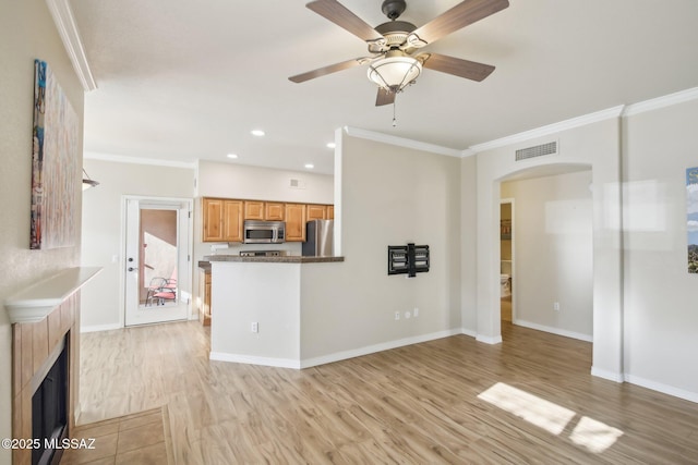 kitchen with stainless steel appliances, crown molding, ceiling fan, and light wood-type flooring