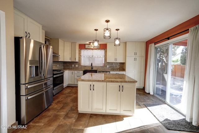 kitchen featuring appliances with stainless steel finishes, a kitchen island, decorative light fixtures, decorative backsplash, and sink