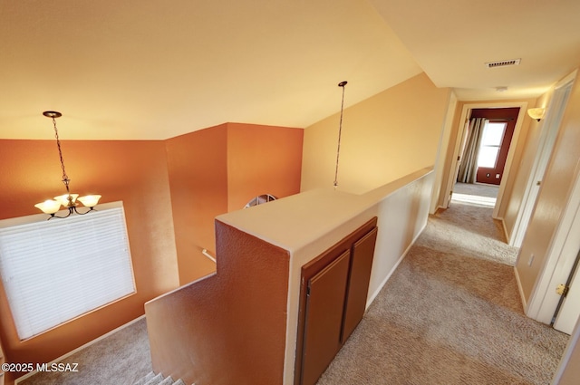 corridor with lofted ceiling, light carpet, and a chandelier