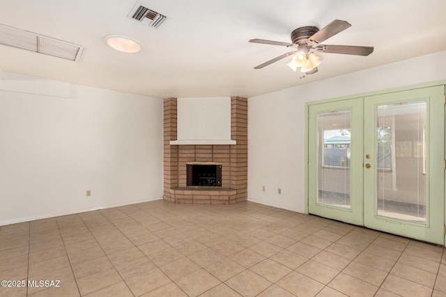 unfurnished living room featuring a brick fireplace, light tile patterned floors, ceiling fan, and french doors