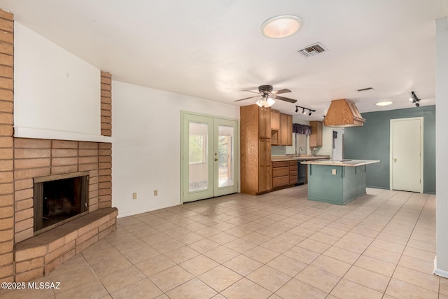 kitchen with sink, a center island, a brick fireplace, dishwashing machine, and ceiling fan