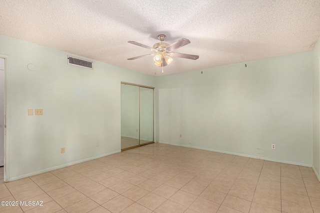 tiled empty room with a textured ceiling and ceiling fan