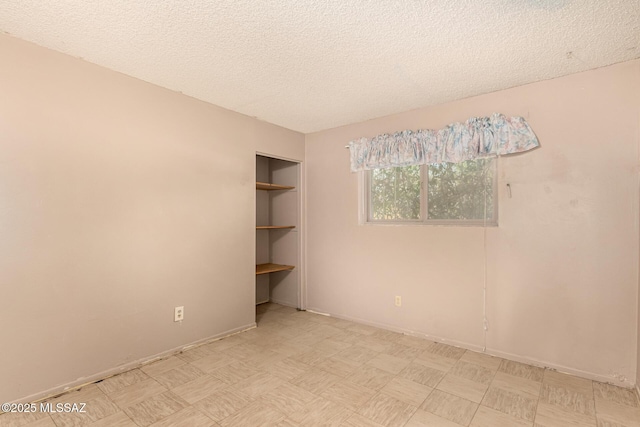 unfurnished room with built in shelves and a textured ceiling