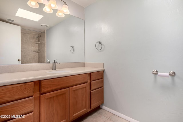 bathroom featuring tile patterned flooring, vanity, a skylight, and tiled shower