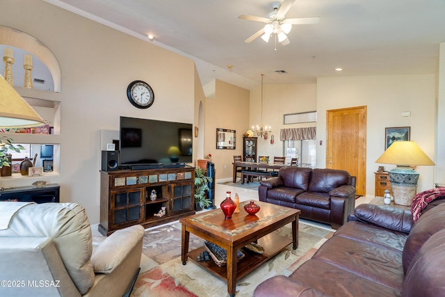 living room with ceiling fan with notable chandelier and vaulted ceiling